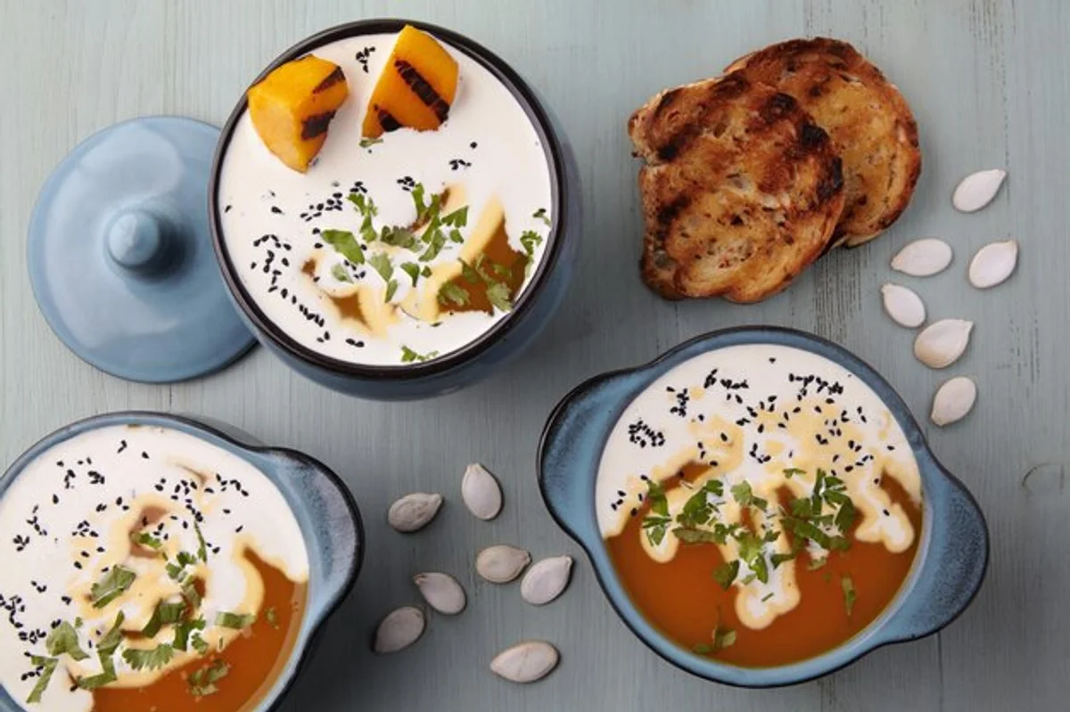 creamy pumpkin soup with seeds and herbs on table autumn