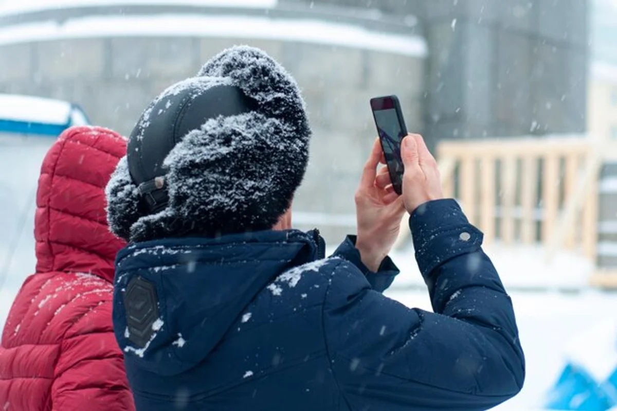 hand warming phone in cold weather