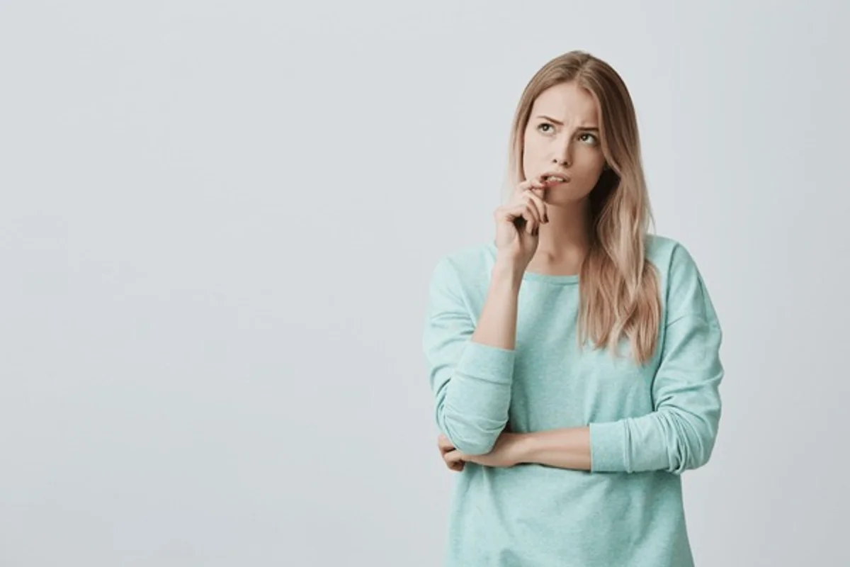 realistic woman holding her head with a confused face, not stressed, indoor, daylight