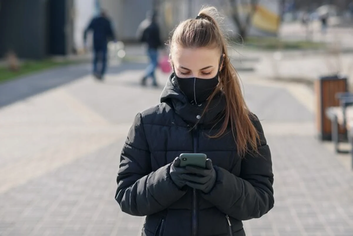 woman using smartphone winter gloves street