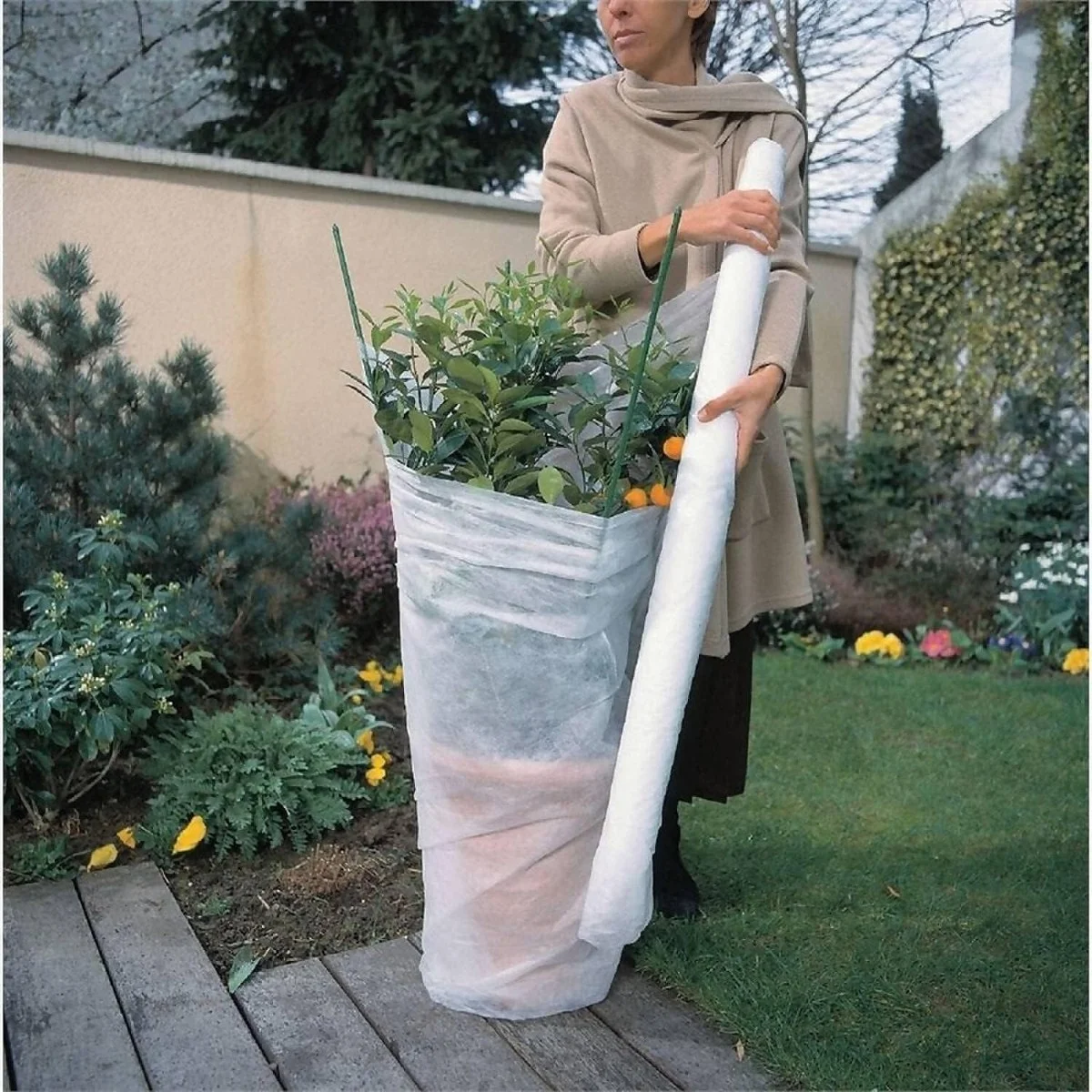 Gardener covering plants with fleece in Czech garden
