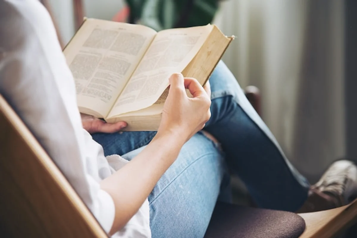 person reading science magazine with autumn leaves outside window